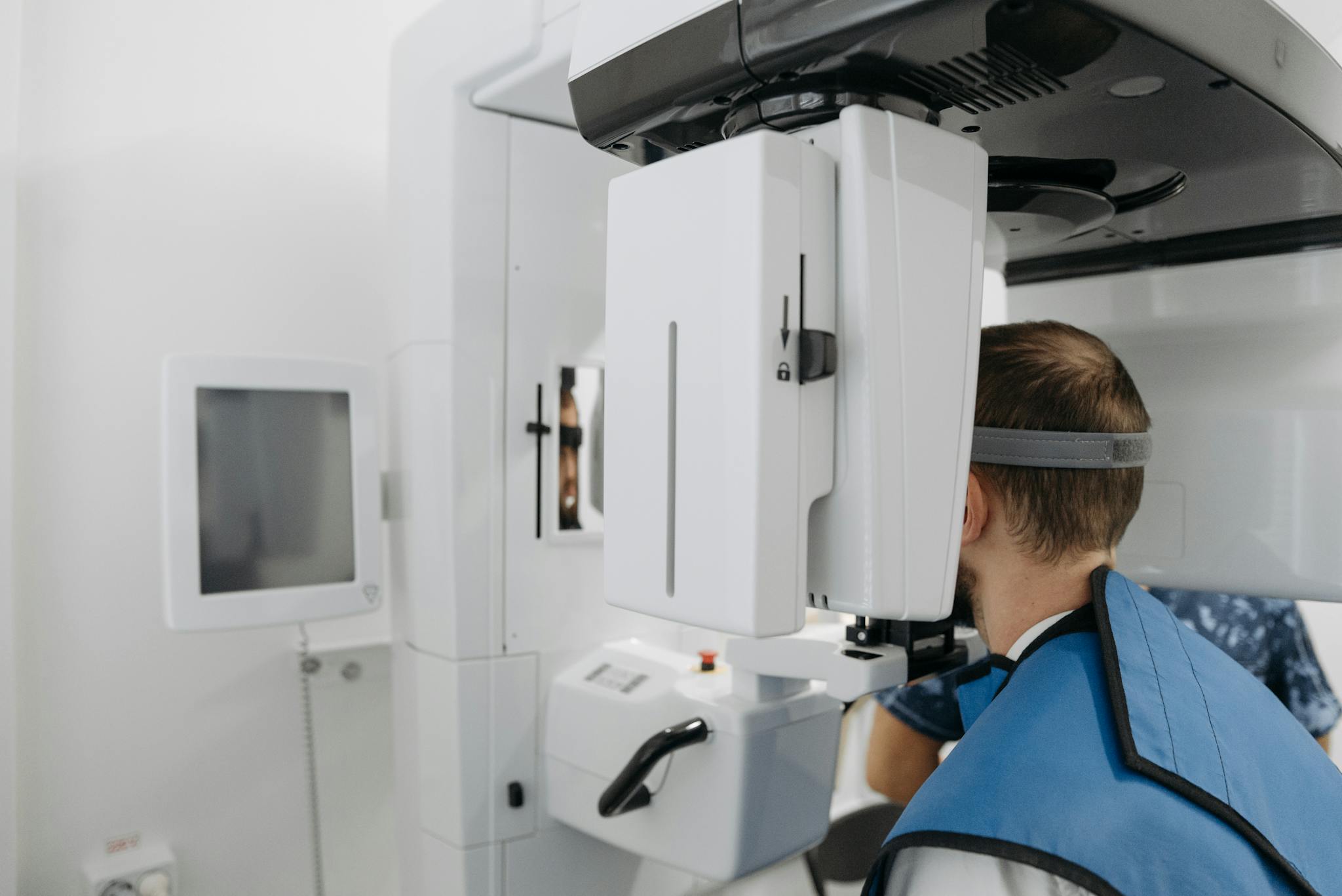 A patient undergoing a dental panoramic X-ray scan in a clinic setting.